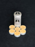 Beeswax tealight storage tin with black patterned design and six tealights with cotton wicks in metal cups displayed in the foreground on a dark background