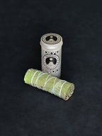 Eucalyptus storage tin with black patterned design and a bundle of Eucalyptus tied with white cotton string displayed in the foreground on a dark background