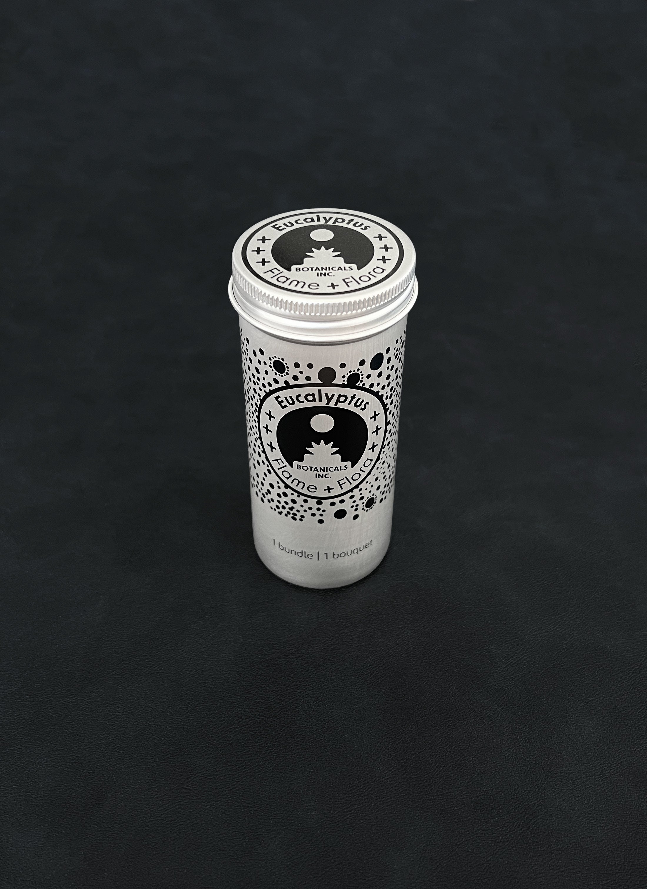 Silver metal storage tin with black patterned design for eucalyptus on a dark background