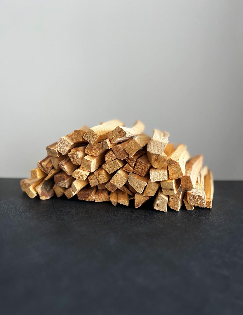 Palo santo sticks stacked like firewood on a dark surface against a white background