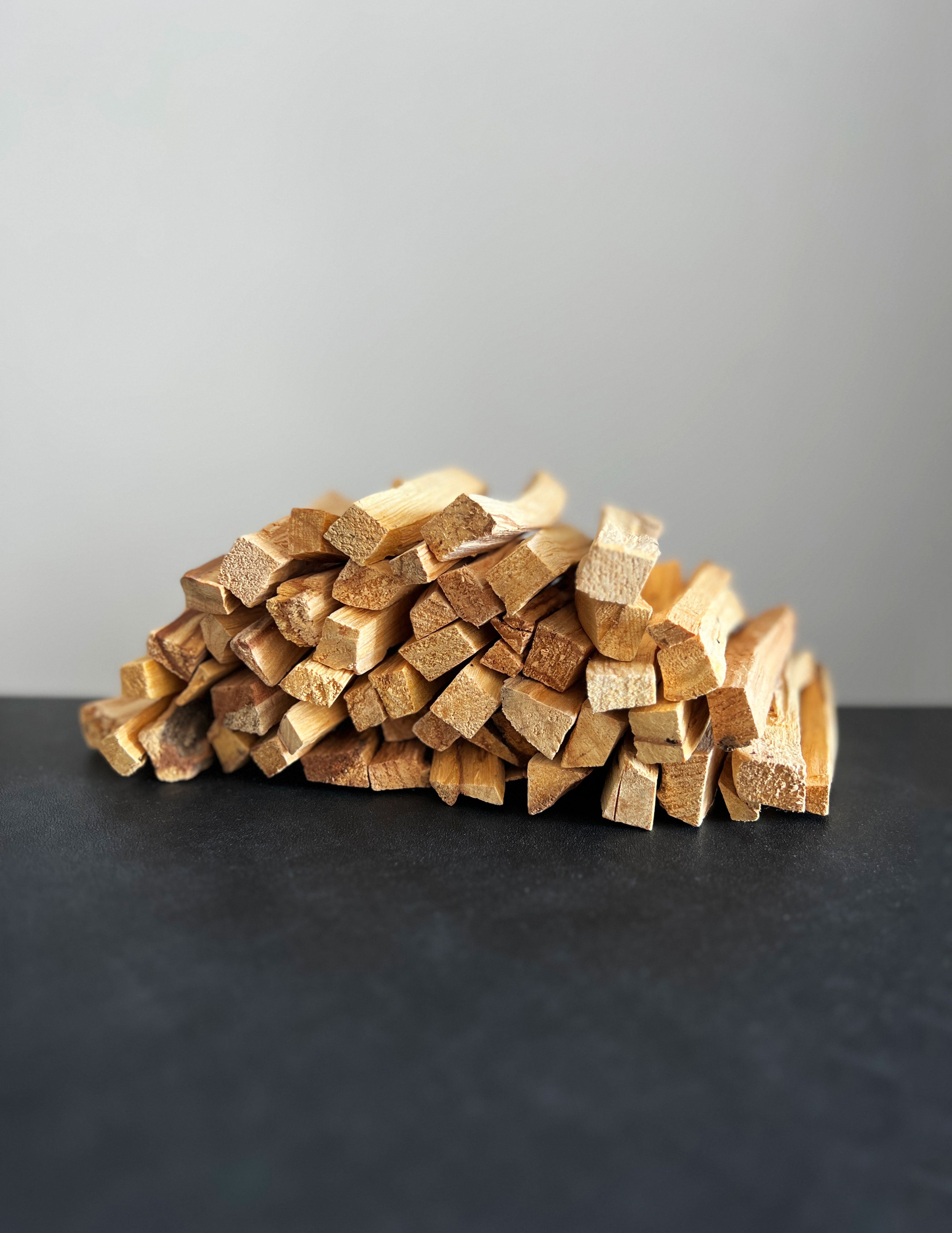 Palo santo sticks stacked like firewood on a dark surface against a white background
