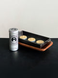 Beeswax tealight storage tin with black patterned design and three beeswax tealights in metal cups displayed with a cast iron incense burner and acacia wood tray set against a white background