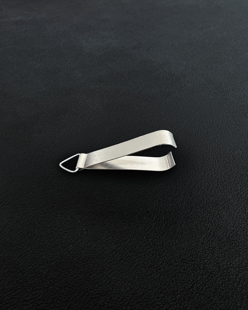 A pair of compact metal incense tongs against a dark background