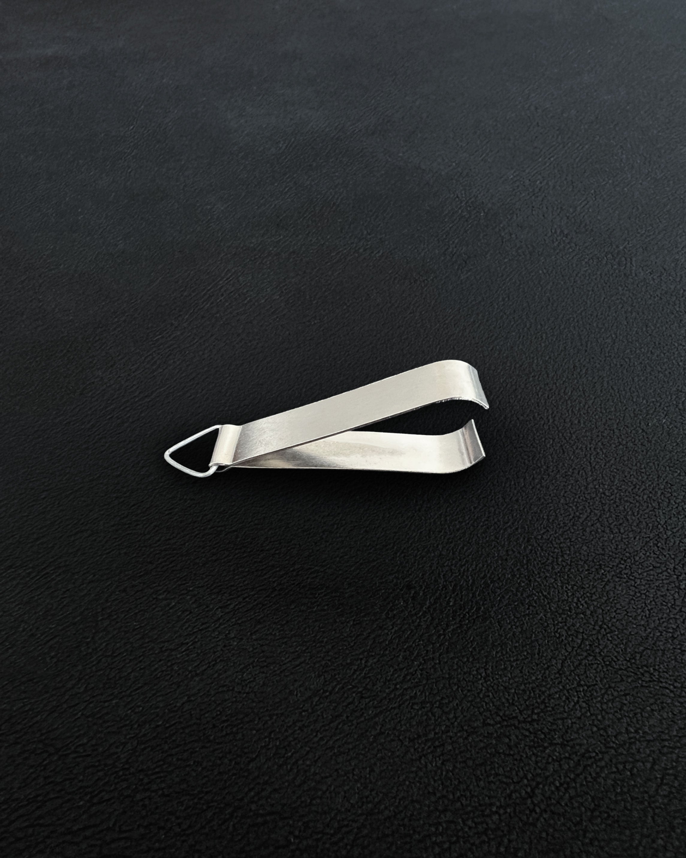 A pair of compact metal incense tongs against a dark background