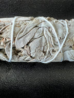 Close-up of White Sage smudge stick bundled with white cotton string on a dark background