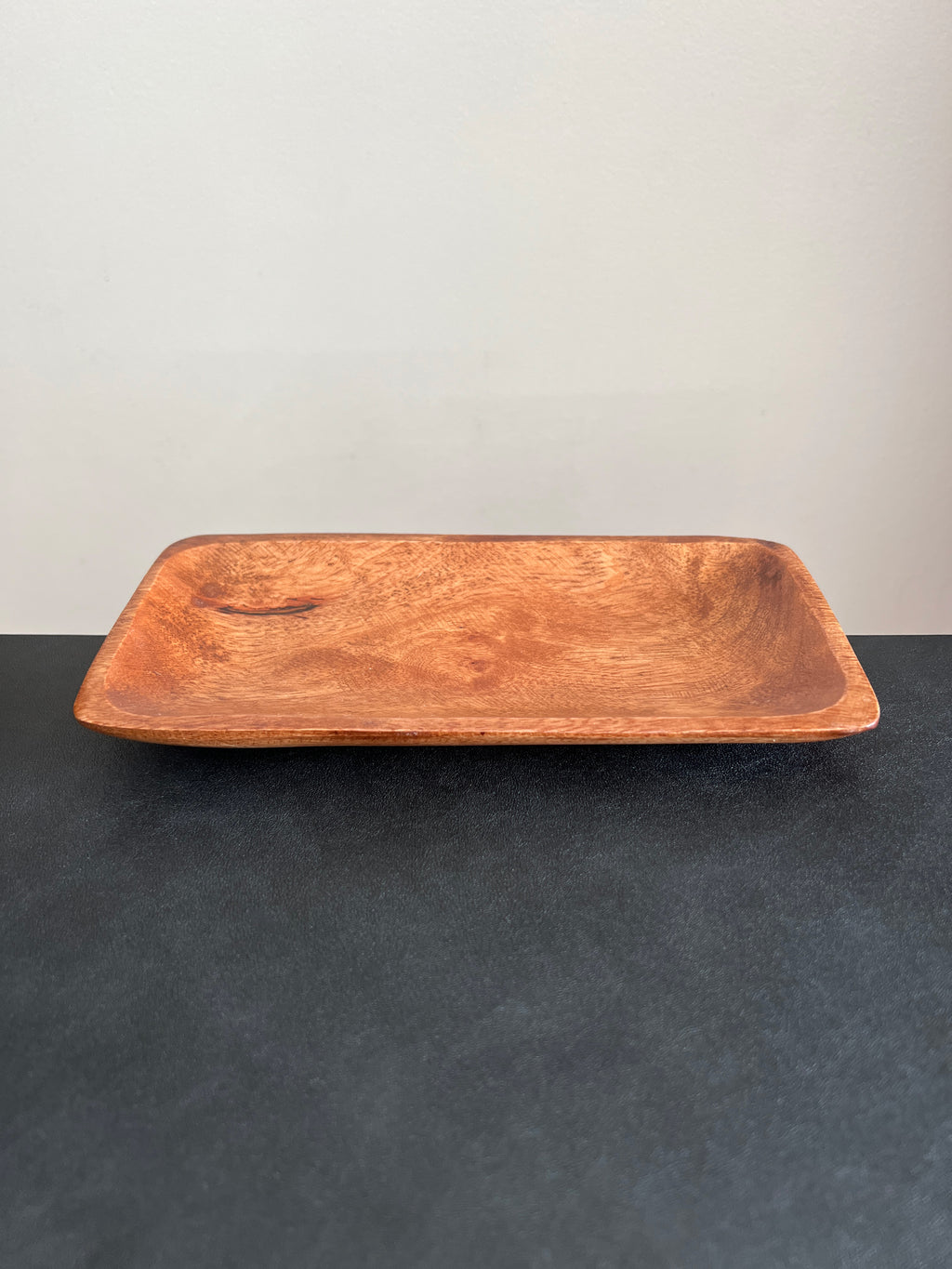 A rectangular acacia wood tray positioned horizontally on a dark surface against a white background