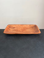 A rectangular acacia wood tray positioned horizontally on a dark surface against a white background