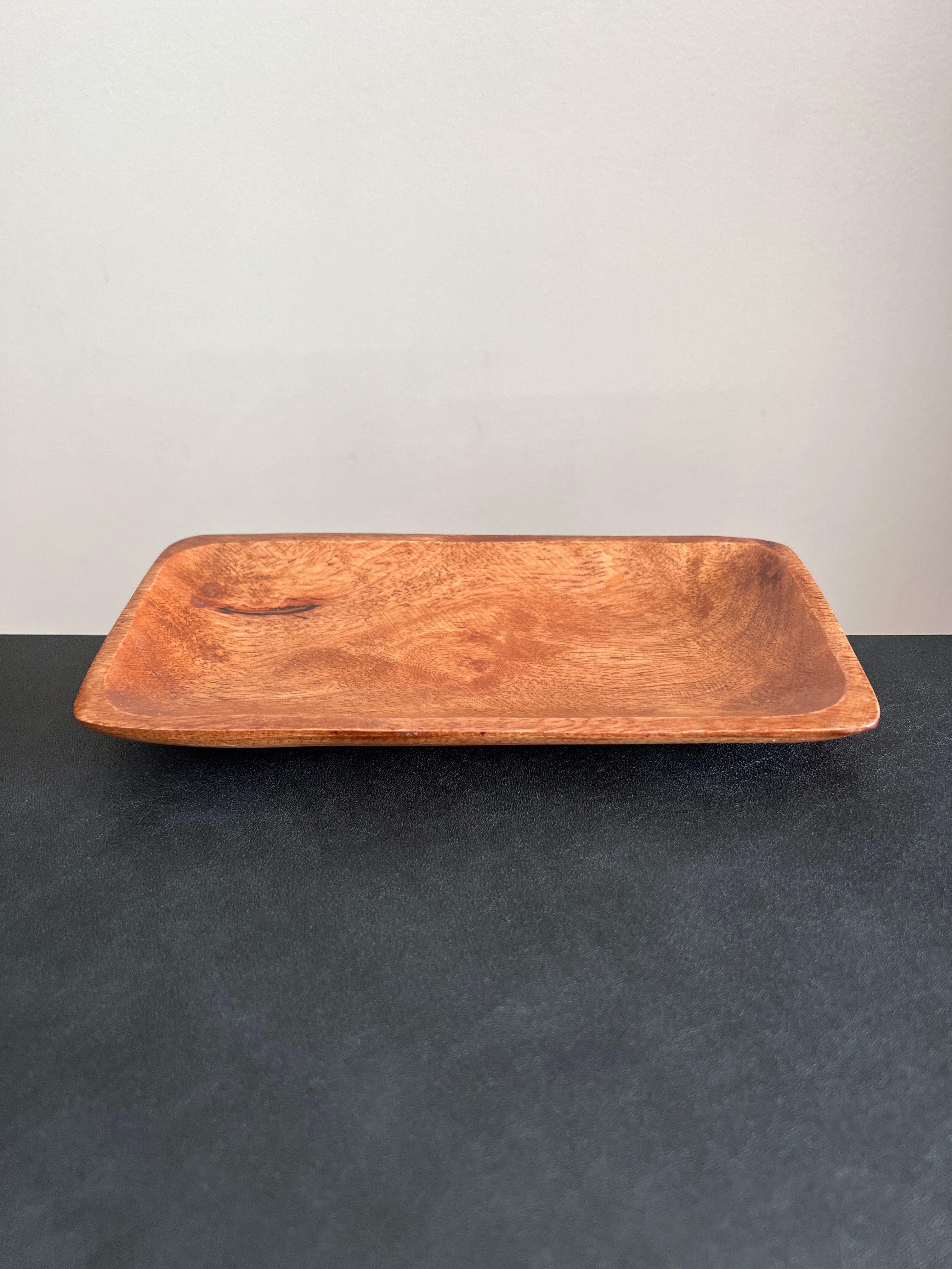 A rectangular acacia wood tray positioned horizontally on a dark surface against a white background